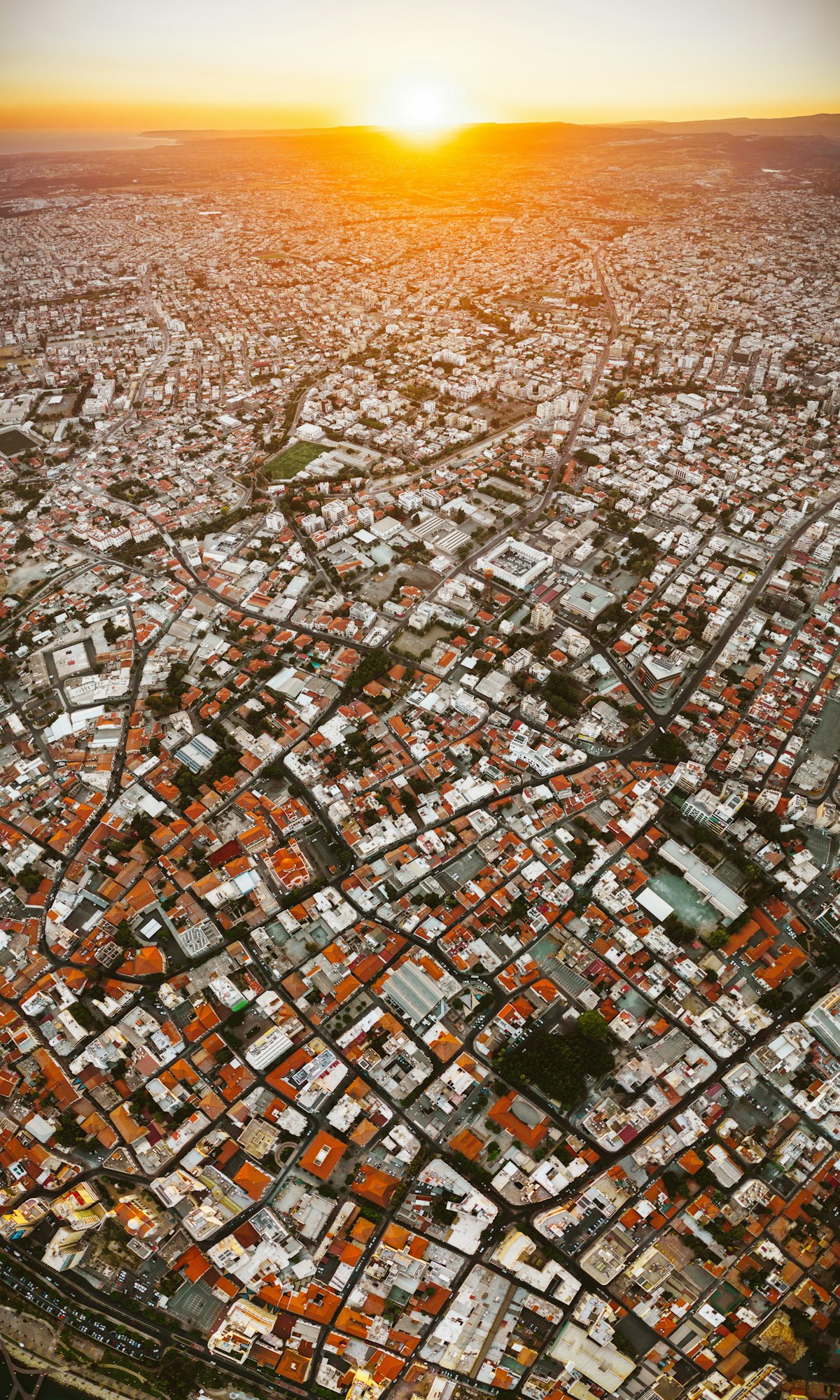 Rooftops of a Cypriot coastal city with a construction crane and port cranes on the horizon