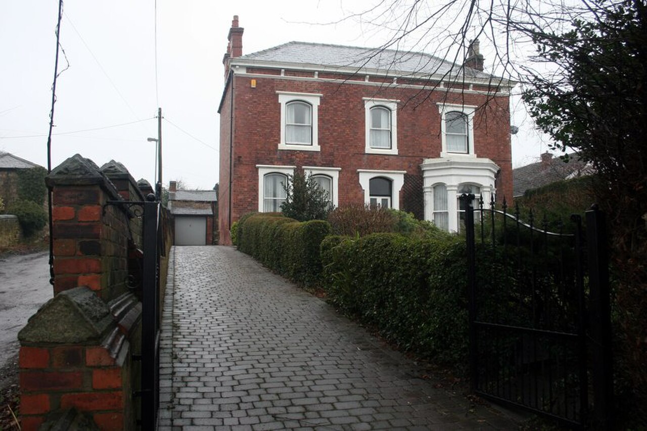 A classic English Victorian red-brick detached house with bay windows and walled driveway