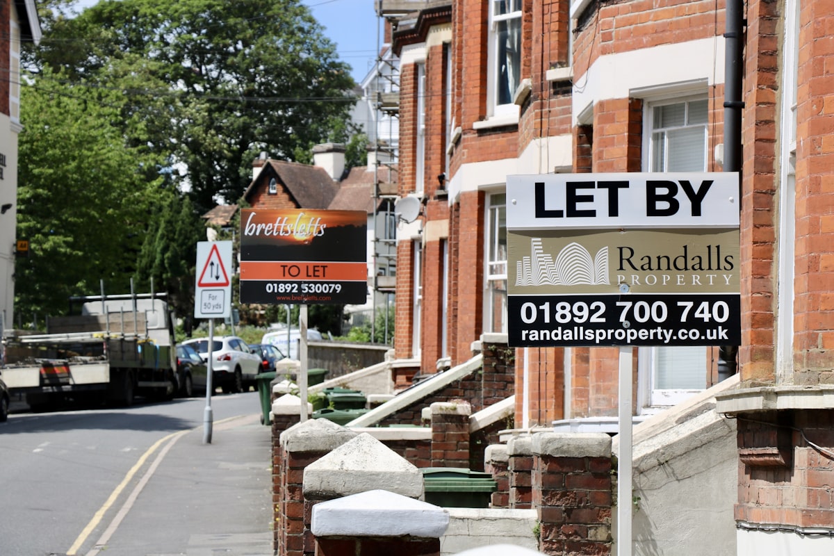 Letting agent boards outside brick terraced houses on a British street